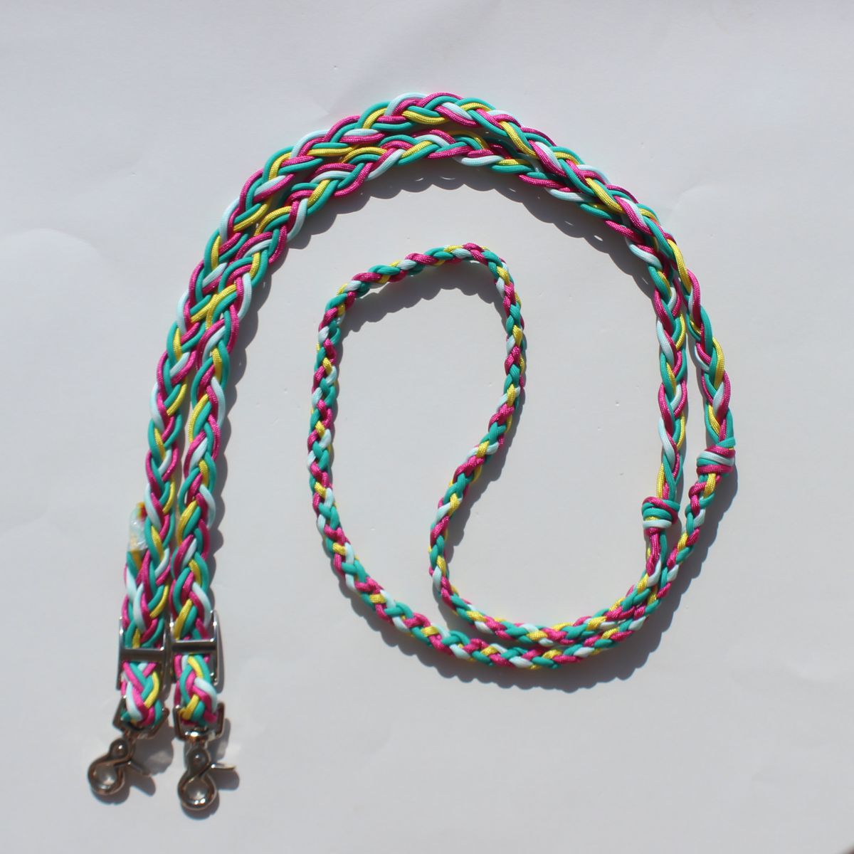 Hand braided nylon barrel reins with a multicolor pattern of pink, green, yellow, and white, featuring silver metal snap hooks at the end.