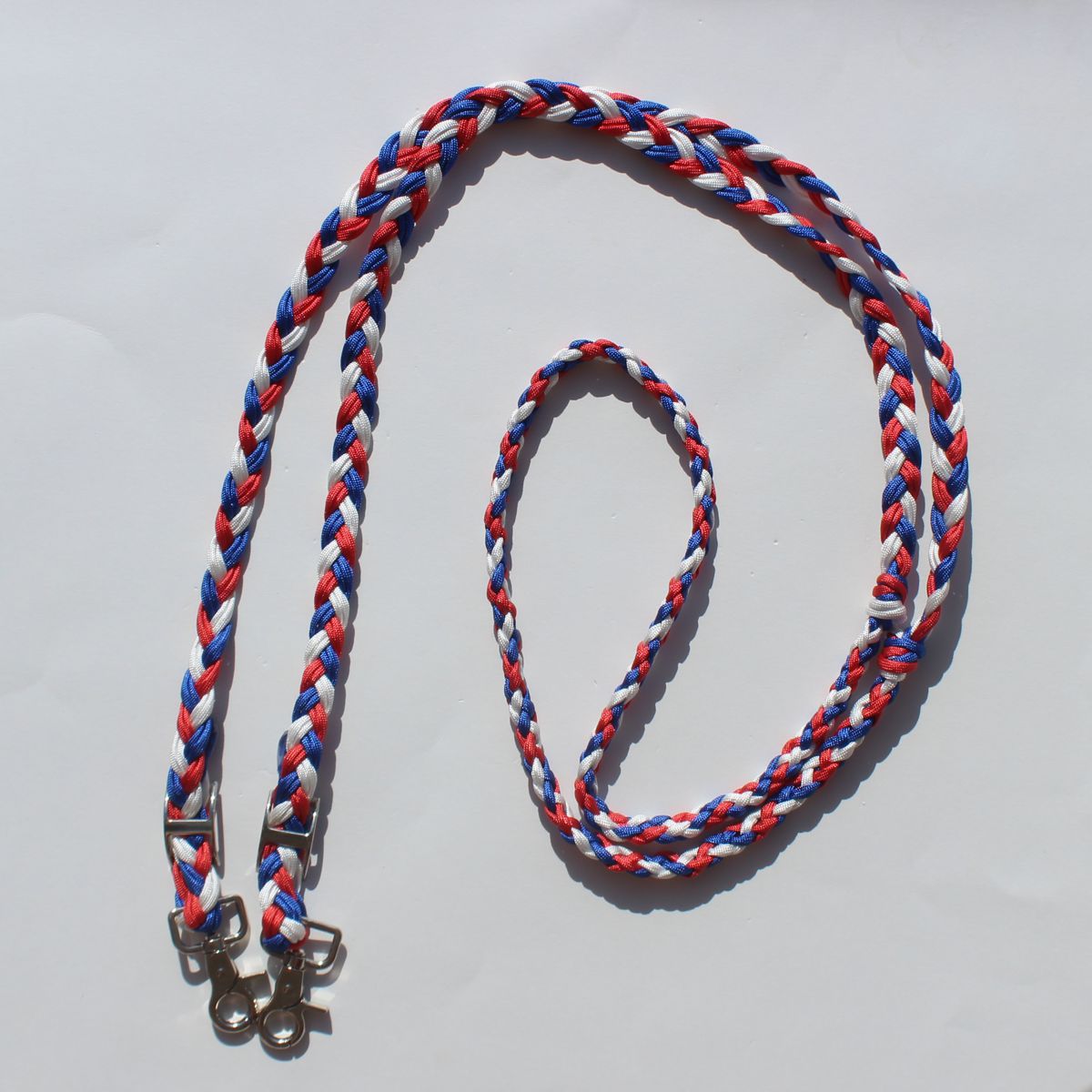 Braided rope barrel reins with silver metal hardware, featuring red, white, and blue strands