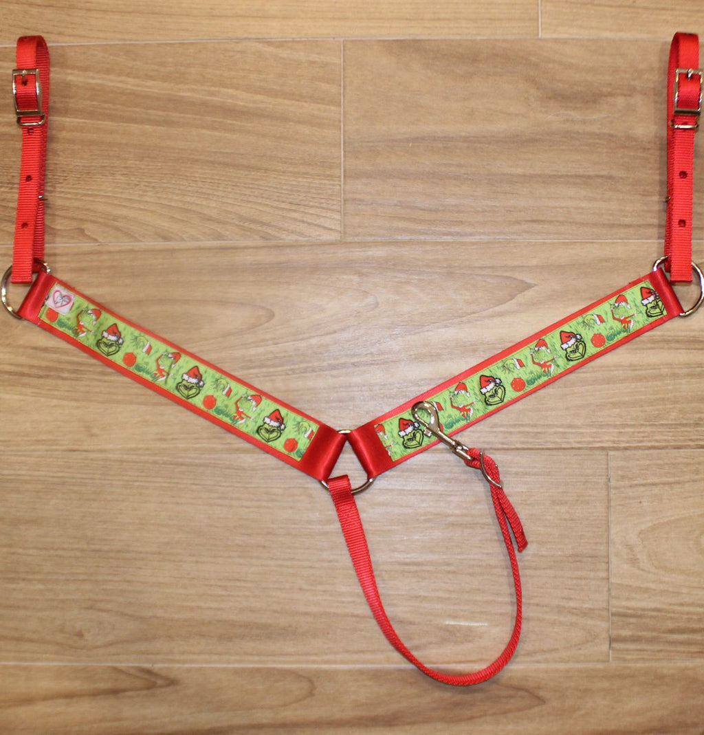 A Christmas-themed horse breast collar featuring red straps, a green patterned center panel and red trim.