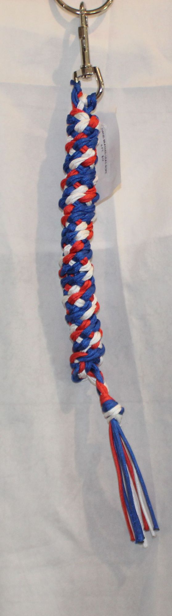 A patriotic red, white, and blue braided lead rope with a silver metal split ring and clasp, shown against a white fabric background.