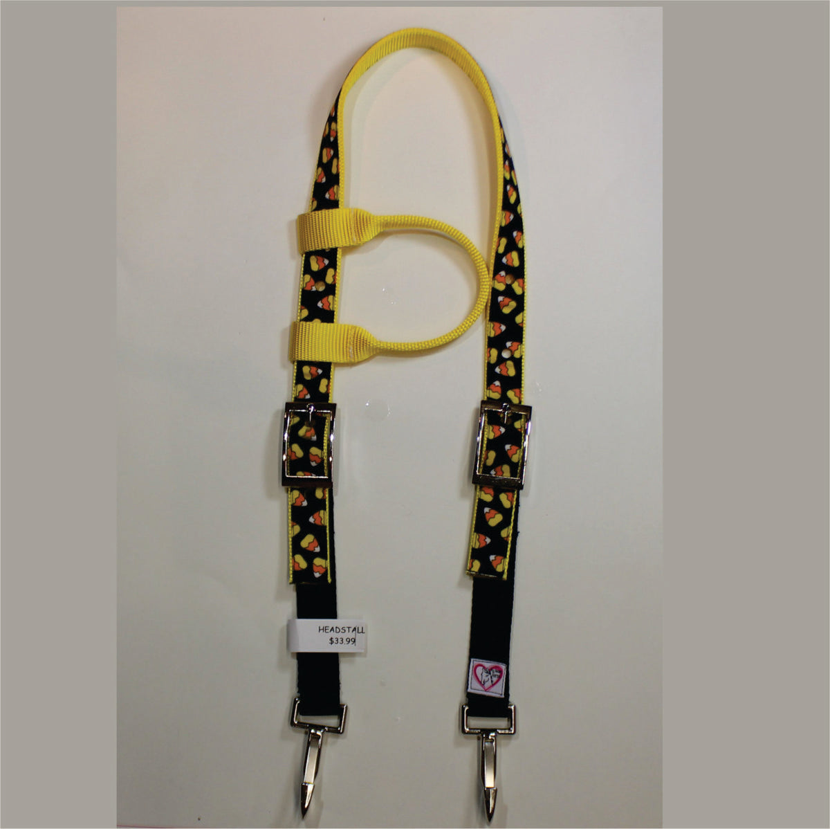 A yellow and black horse headstall with a candy corn pattern, featuring silver metal buckles, clips.