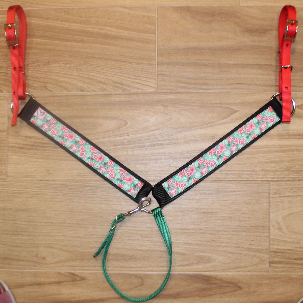 Christmas horse breast collar has red nylon tug straps, black trim, and a candy patterned center panel in red, green, and white.