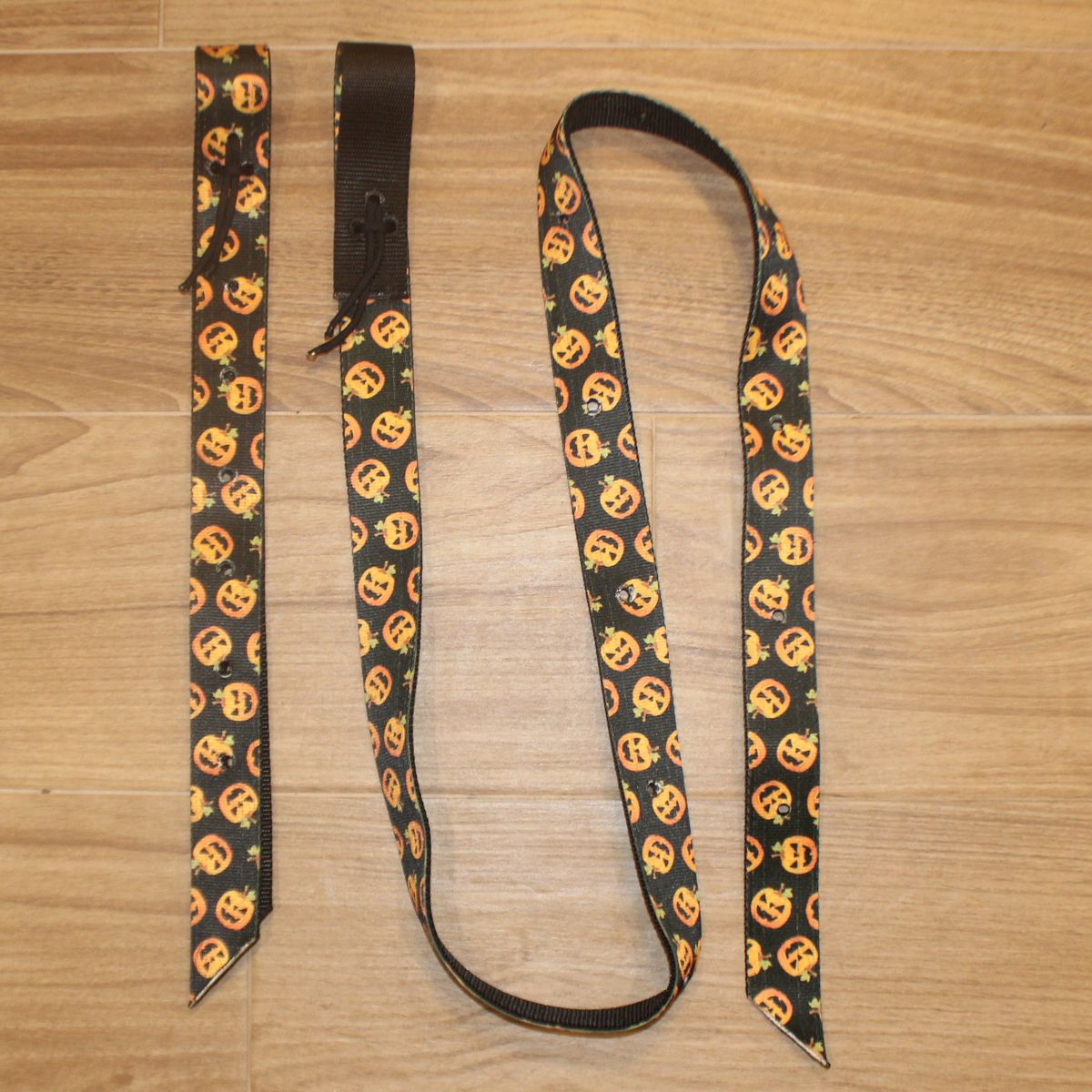 A Halloween-themed horse cinch set with a black background and a repeating pattern of orange jack-o'-lantern faces, 
