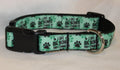 A pet collar with a mint green and black pattern featuring paw prints and the text 'I LIKE BIG BONES AND I CANNOPT LIE'. The collar has a black plastic buckle and a silver metal ring, 