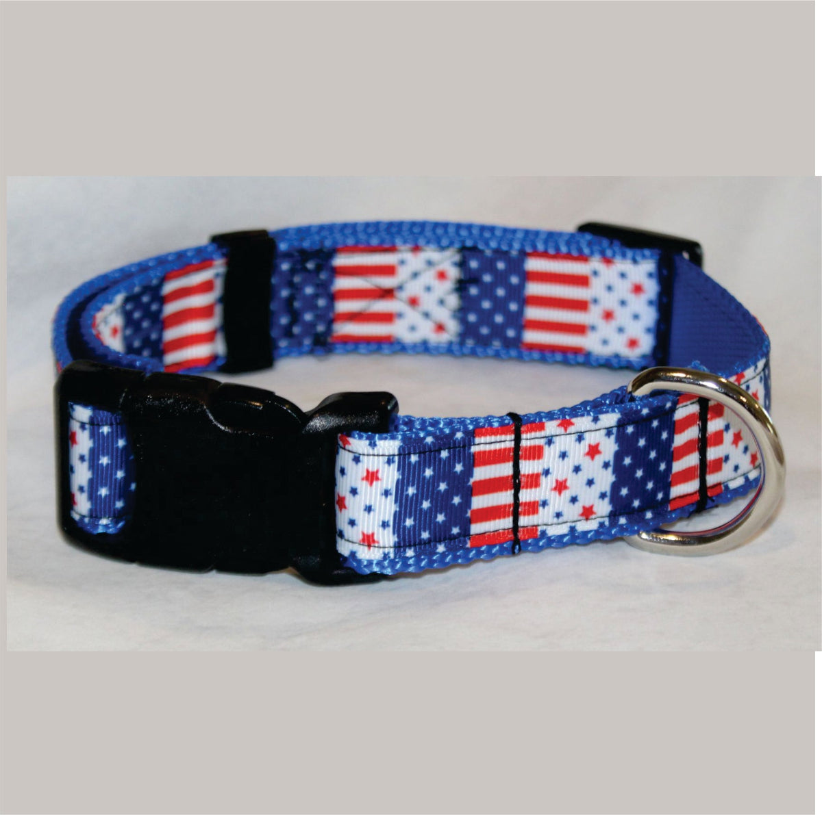 A patriotic-themed dog collar featuring a red, white, and blue American flag pattern with a black plastic quick-release buckle and a silver metal ring