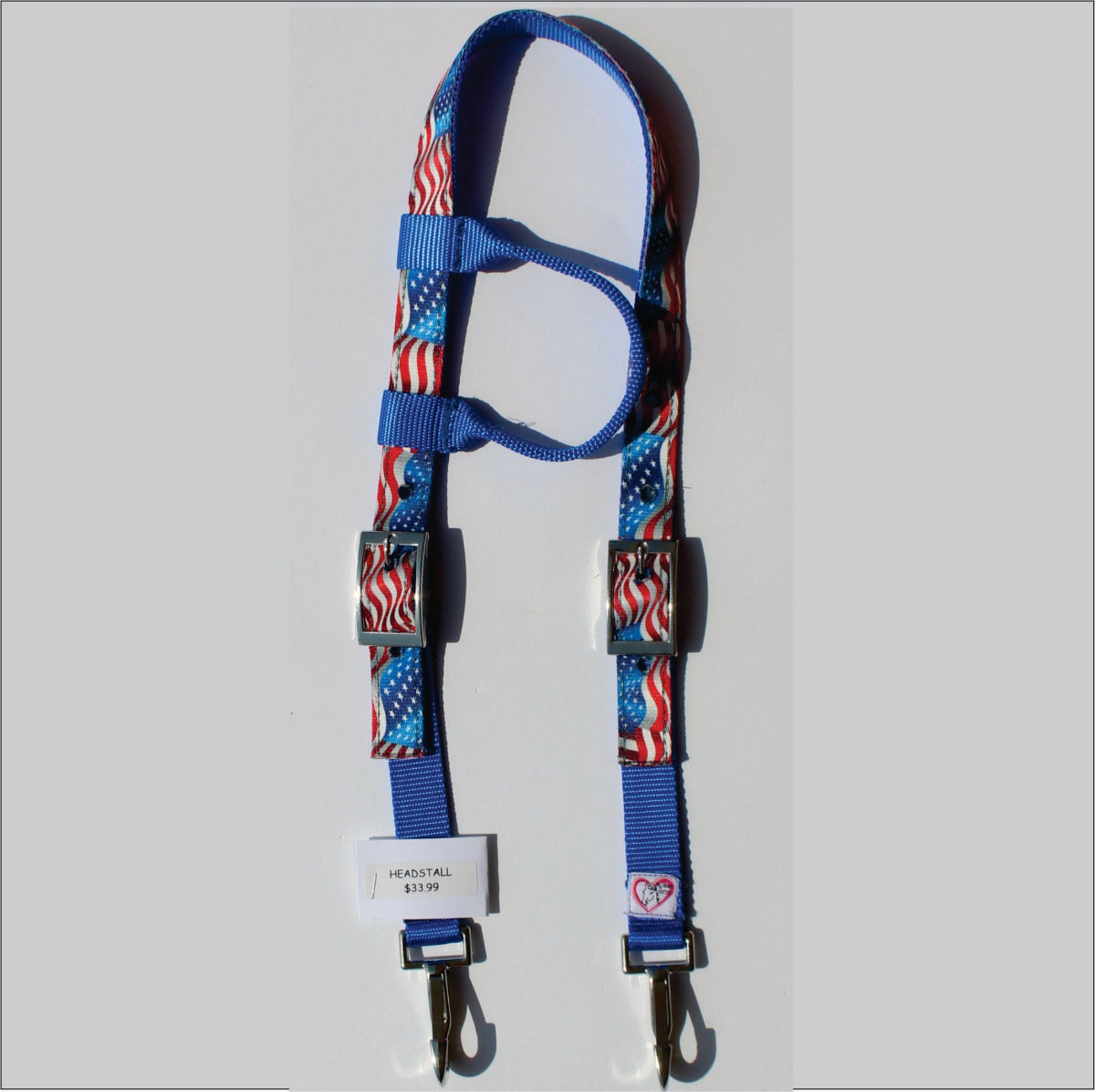 A patriotic-themed horse headstall featuring a blue webbed base with red, white, and blue American flag and stars-and-stripes patterns.