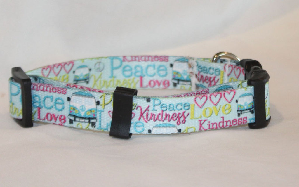 A nylon  dog collar with a colorful pattern of text reading 'Peace', 'Love', and 'Kindness' alongside small illustrations of vans and hearts, featuring black plastic buckles on a light background.