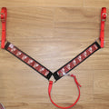 A red and black plaid horse breast collar with reindeer details, red straps