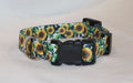 A dog collar with a vibrant sunflower print on a white background, featuring black plastic quick-release buckles and a silver metal ring.