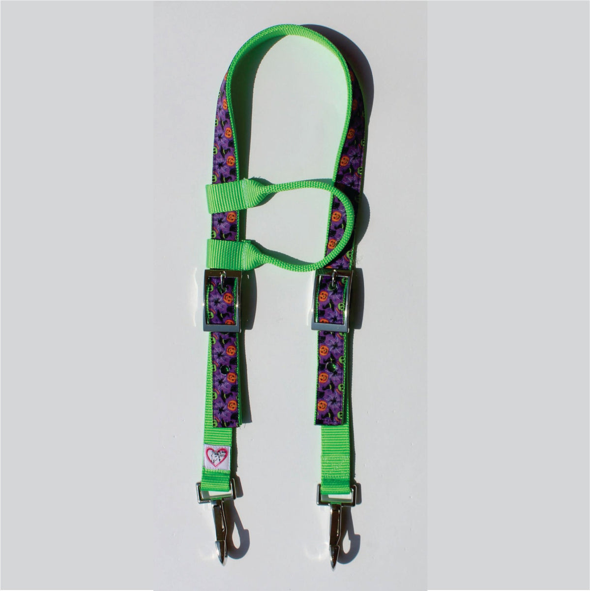 A horse headstall with bright green webbing and purple halloween straps, featuring metal buckles and clips, 